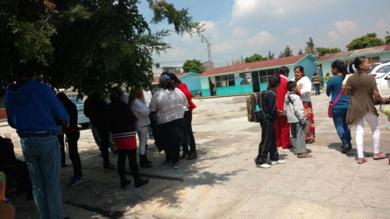 Padres de familia esperan a sus hijos a la salida de la escuela