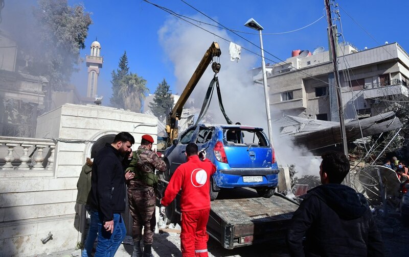 Rescatistas retiran un coche de entre los escombros de un edificio en Siria