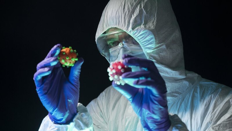 Científico sosteniendo dos modelos de coronavirus