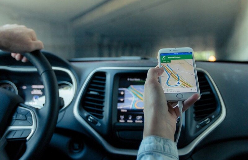 Mujer usando un teléfono móvil como GPS mientras conduce