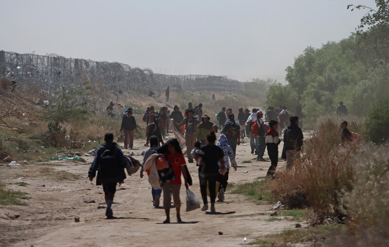 Migrantes caminan por un camino en la frontera entre México y Estados Unidos