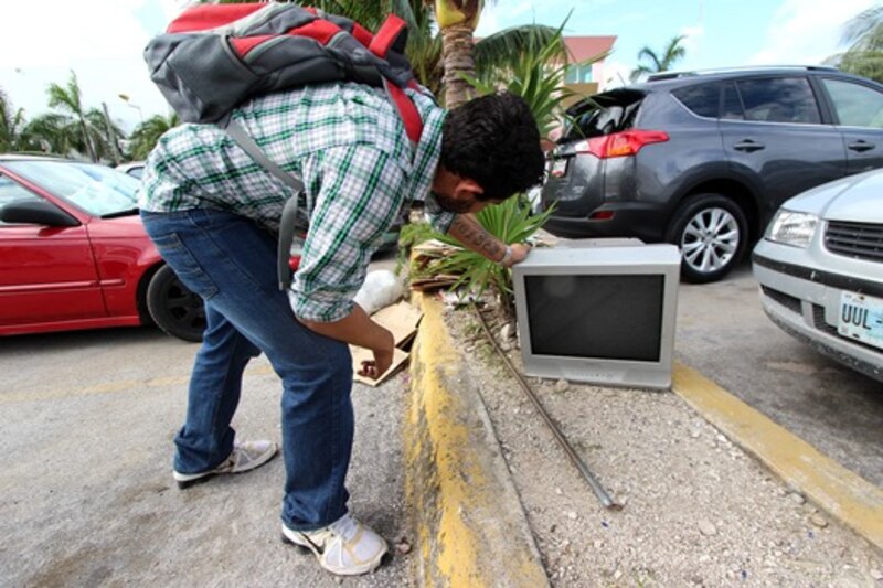 Un hombre recoge un televisor de la basura