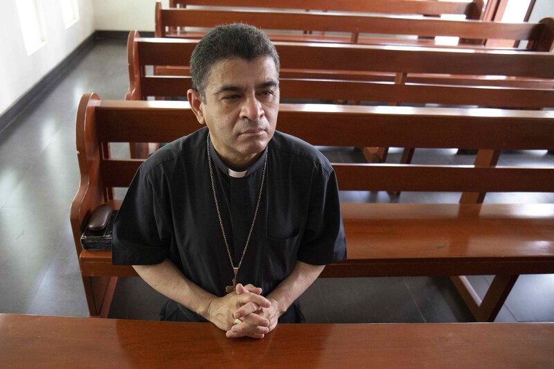 Sacerdote sentado en una banca de la iglesia