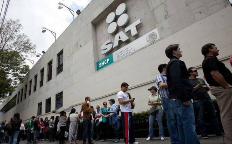 Larga fila de personas afuera de una oficina del SAT