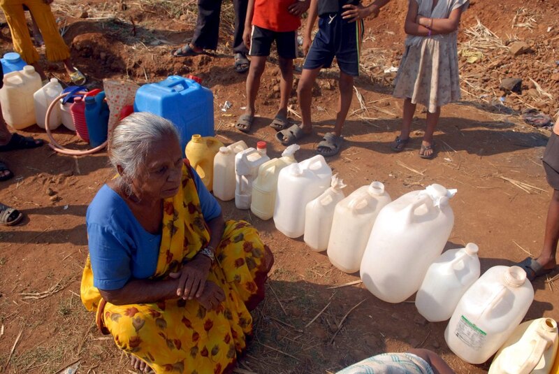 Título: Mujer india con sari amarillo sostiene una botella de agua en la India rural