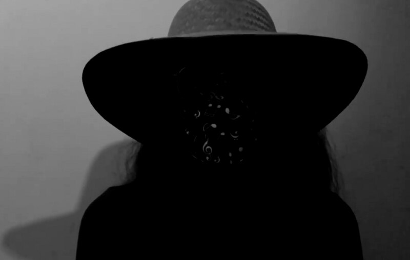 Mujer con sombrero negro y máscara de música