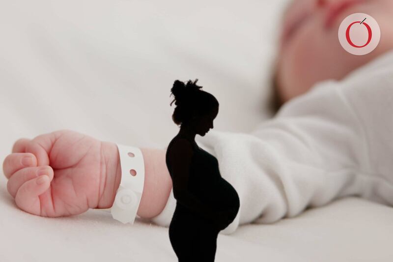 Imagen de un bebe acostado sobre una cama y silueta de mamá embarzada