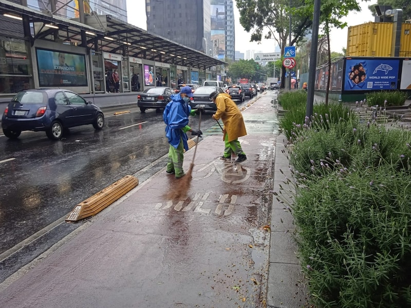 Dos barrenderos limpian una ciclovía en la Ciudad de México