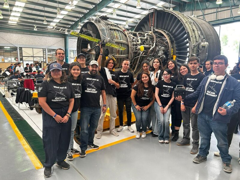 Estudiantes de ingeniería aeronáutica posan junto a un motor de avión.