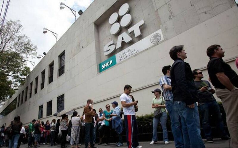 Larga fila de personas esperando para entrar al SAT