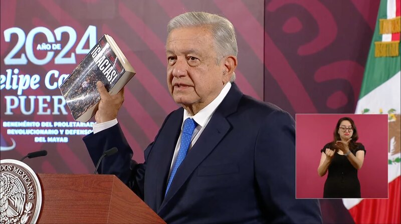 El presidente Andrés Manuel López Obrador sostiene un libro durante una conferencia de prensa.