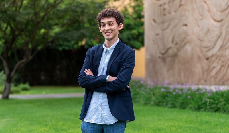 El joven sonríe con los brazos cruzados