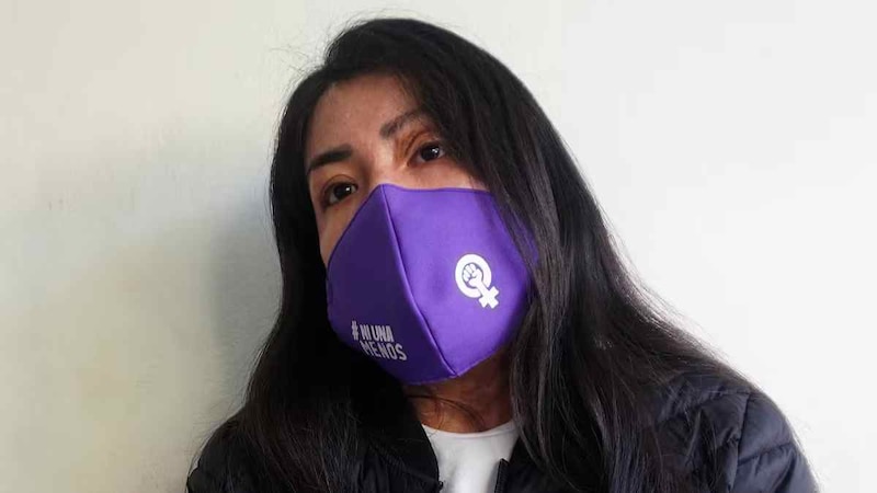 Mujer con tapabocas morado con el símbolo de género femenino