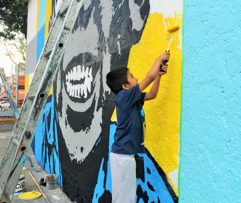 Niño pintando un mural de Cantinflas