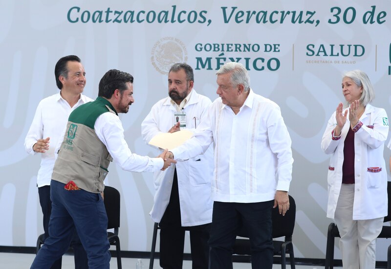 El presidente Andrés Manuel López Obrador entrega un documento a un trabajador del IMSS en Coatzacoalcos, Veracruz.