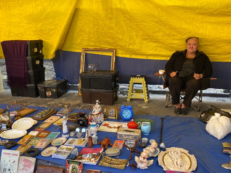Una mujer vende antigüedades en un mercado de pulgas.