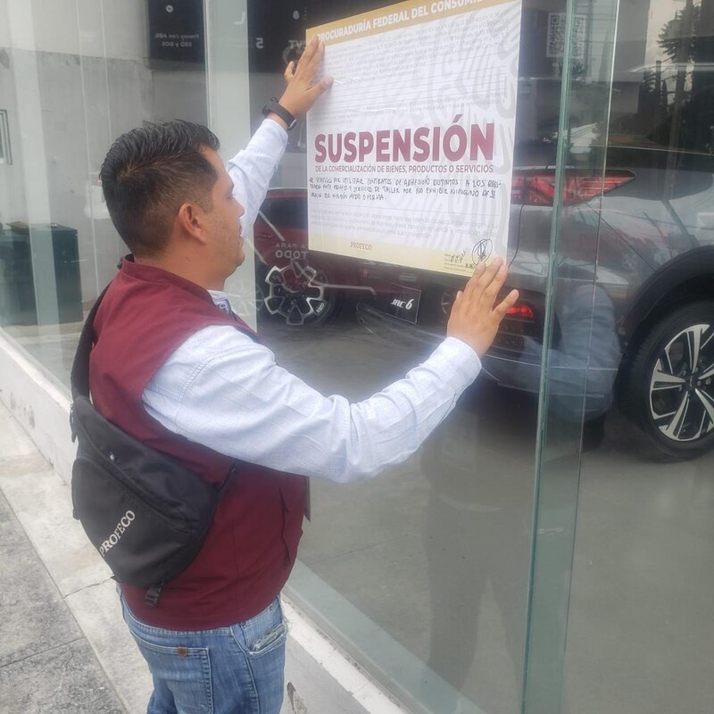 Servidor publico de la Procuraduría Federal del Consumidor coloca sellos de suspensión de actividades en la automotriz JAC en Aguascalientes, México