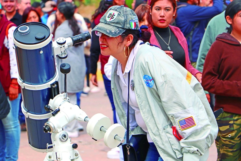 Mujer mirando por un telescopio