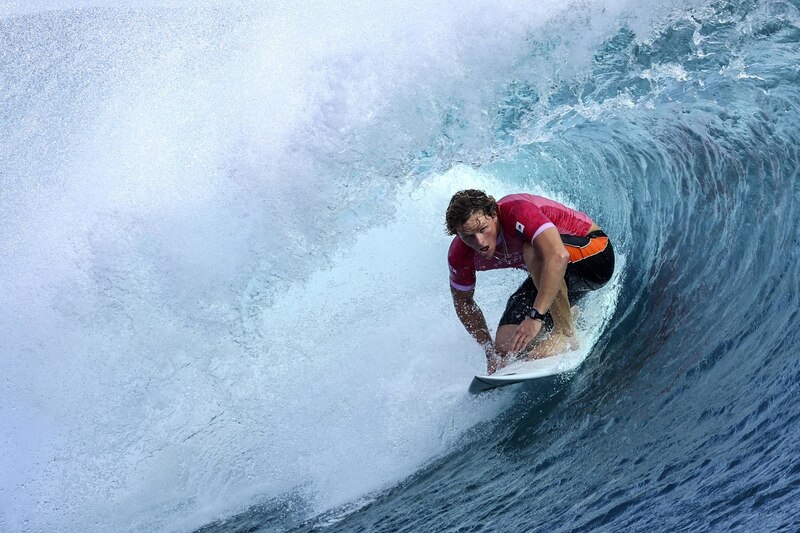 Surfista profesional realizando una maniobra radical en una ola grande.