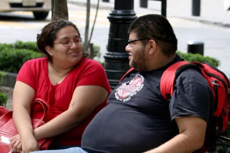 Pareja con sobrepeso sentada en una banca
