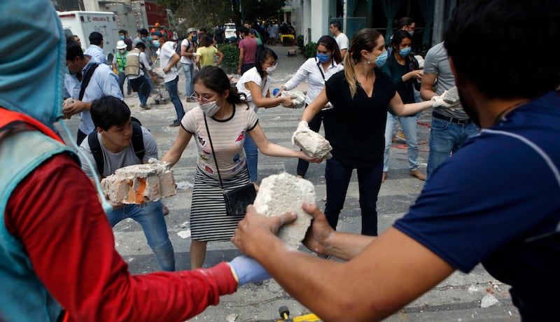 Un grupo de personas se ayuda para levantar escombros tras un terremoto.