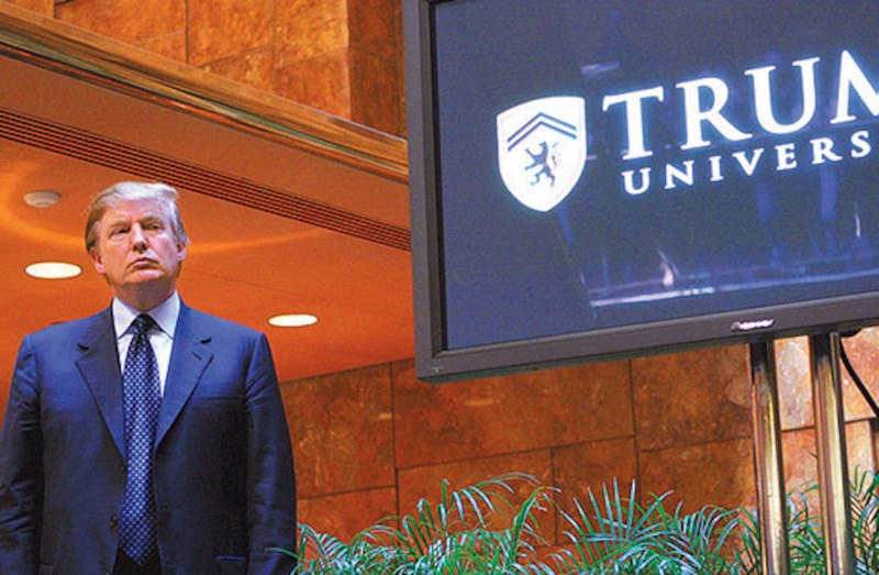 Donald Trump mirando fijamente en un monitor que muestra el logo de Trump University
