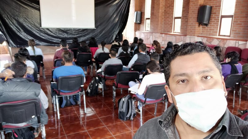 Profesor con cubrebocas dando clase a un grupo de estudiantes