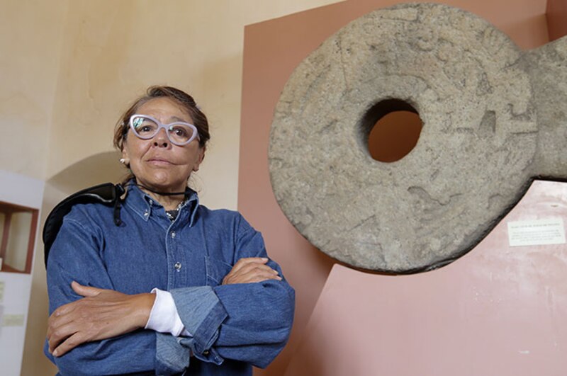 Arqueóloga mexicana frente a un disco de piedra azteca