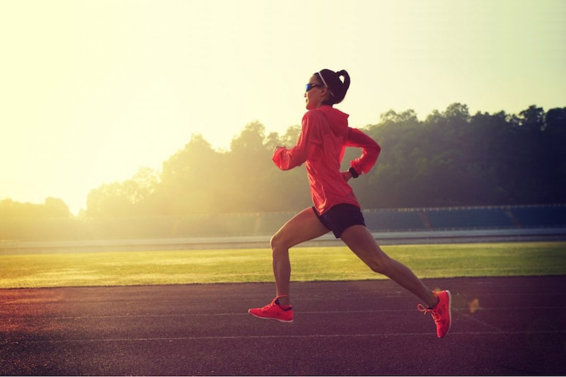 Mujer corriendo en una pista al amanecer