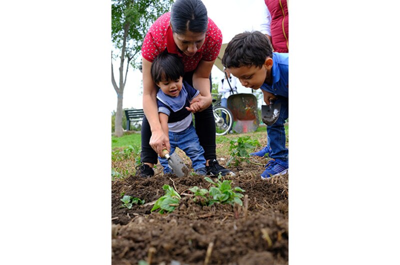 Madre e hijos plantando en el jardín