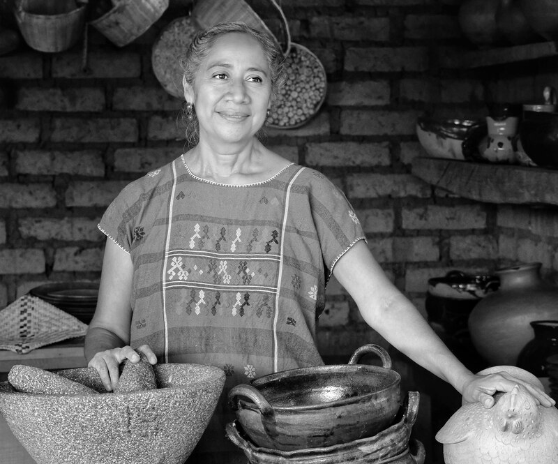 Mujer oaxaqueña en su cocina sosteniendo utencilios