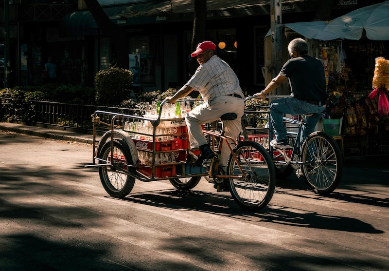 Hombres en bicicleta transportando botellas de cristal