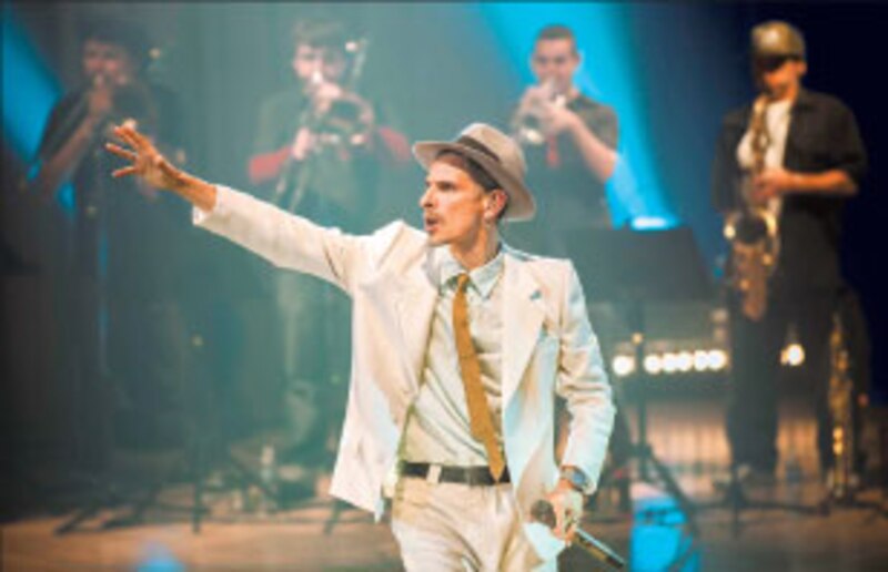 Cantante con sombrero blanco y traje blanco en el escenario