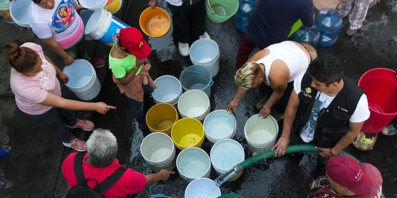 Personas se abastecen de agua en una toma clandestina