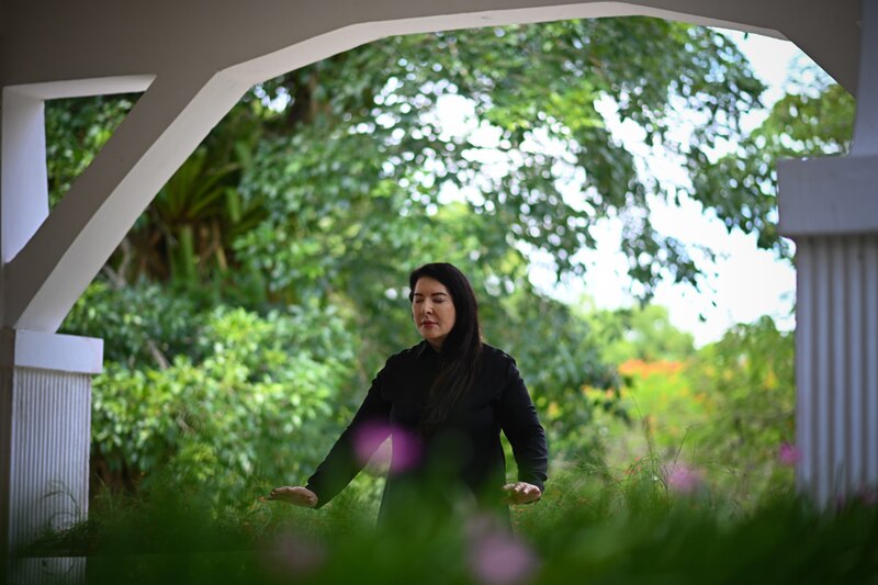 La artista Marina Abramovic realiza una performance en un jardín.