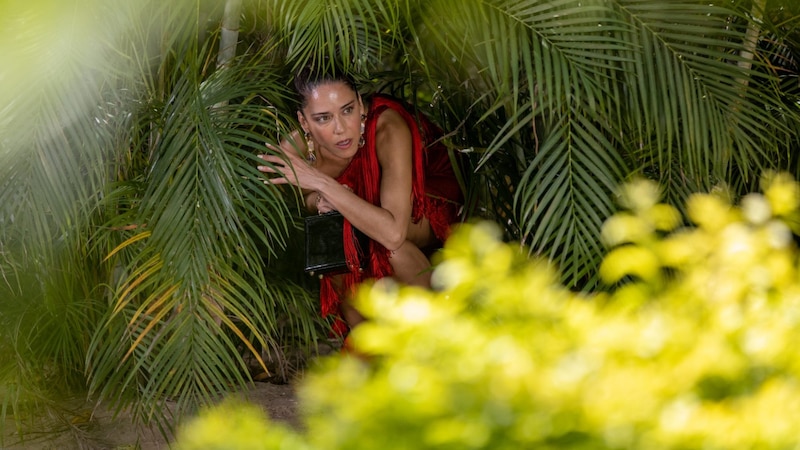 Mujer en vestido rojo se esconde en la selva