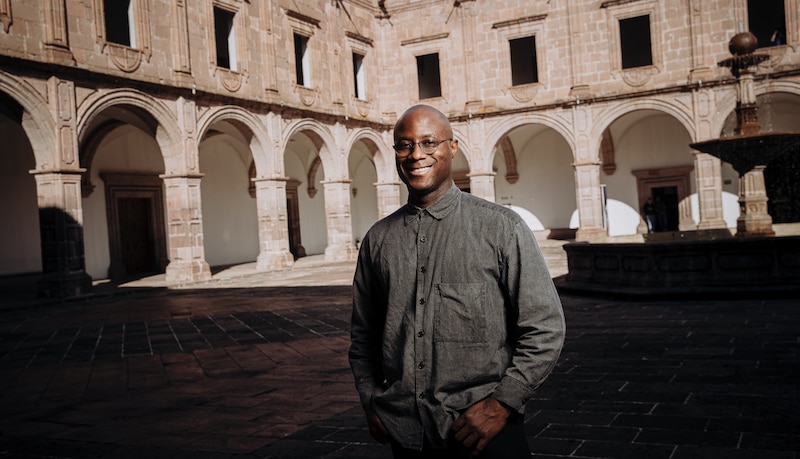 Un hombre negro sonríe en un patio colonial