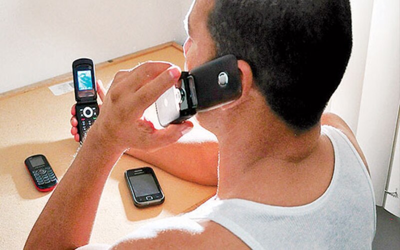 Un hombre sostiene tres teléfonos móviles en la mano