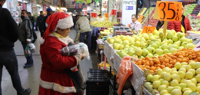 Mujer vestida de Santa Claus compra fruta en un mercado mexicano