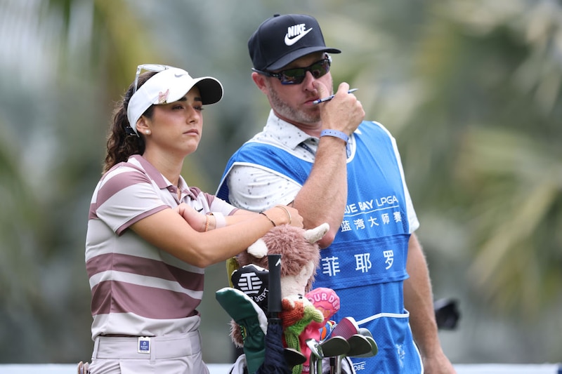 La golfista profesional Lydia Ko observa cómo su caddie, Michael Brooker, apunta a su objetivo durante una ronda del LPGA Tour.