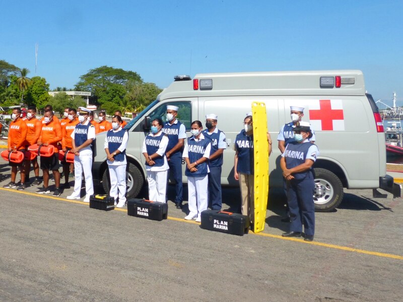 Personal de la Marina en formación junto a una ambulancia.