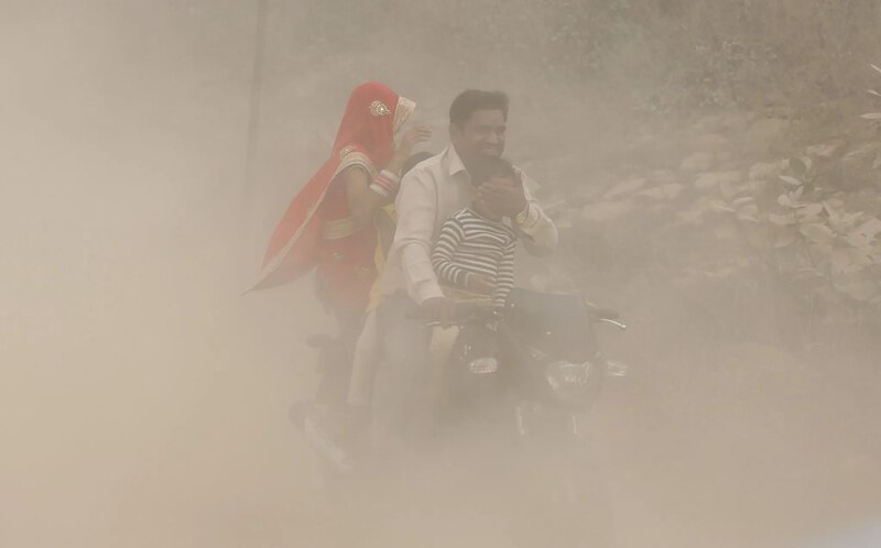 Familia en moto en medio de una tormenta de arena