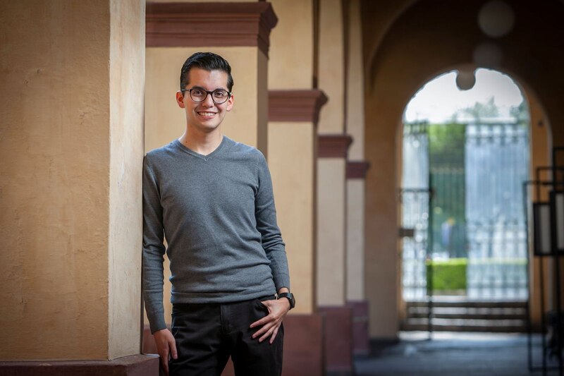 Un joven profesional sonríe a la cámara.