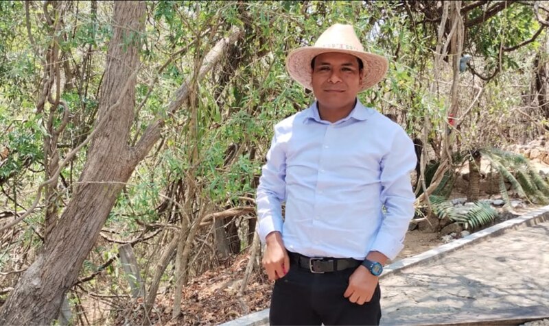 "Un hombre con sombrero y camisa blanca en un bosque"