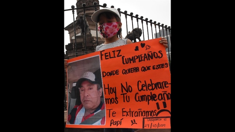 Niña sostiene un cartel con un mensaje para su padre desaparecido