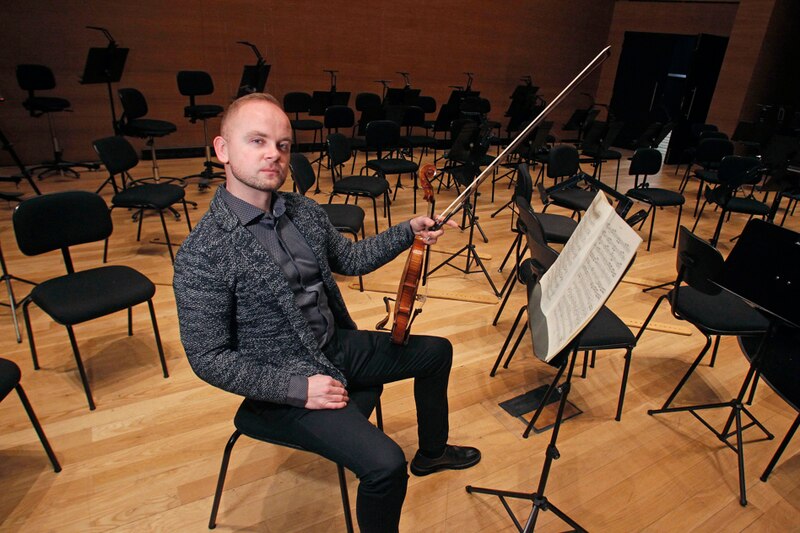 Violinista sentado en una silla en un auditorio vacío