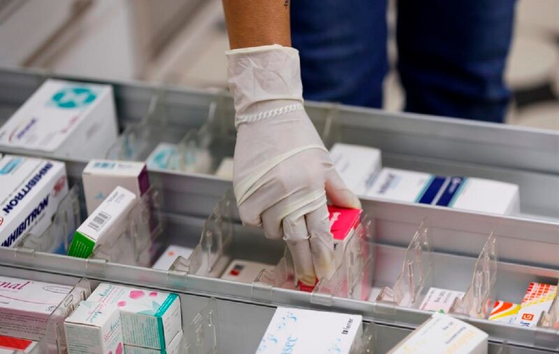 Mujer tomando medicamentos de un estante en una farmacia