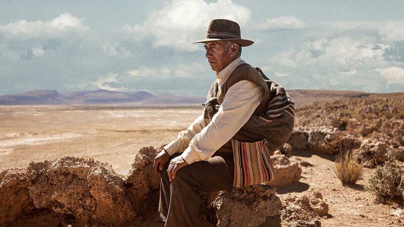 Un anciano sentado en una roca en el desierto
