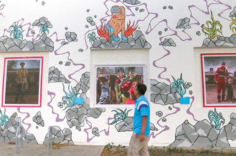 Un hombre camina frente a un mural de arte urbano.