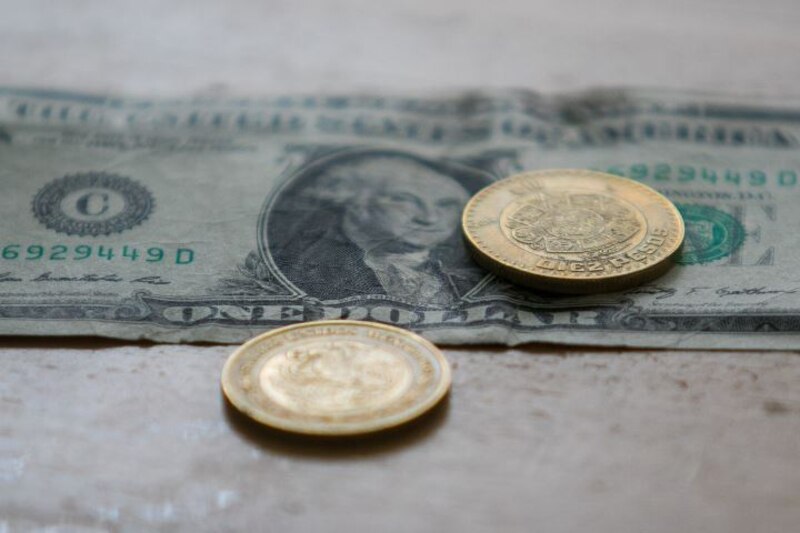 Monedas mexicanas sobre un billete de un dólar estadounidense